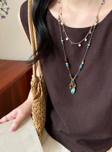 Vue rapprochée d'un collier ethnique en perles avec pendentif turquoise porté par un modèle