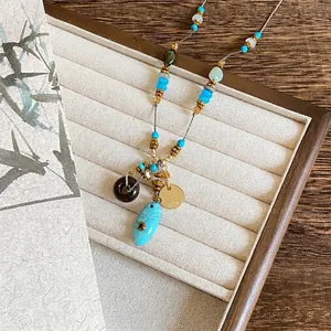 Gros plan d'un collier de perles bohème avec pendentif turquoise et breloque en or