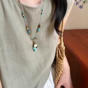 Gros plan d'un collier de perles style ethnique avec pendentif turquoise porté par un modèle