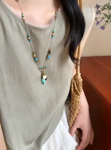 Détail du collier bohème avec perles colorées et pendentif turquoise sur le modèle