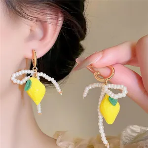 Close-up of fresh lemon pendant earrings with elegant pearl bow design for summer