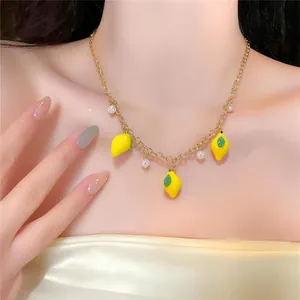Close-up detail of a fresh lemon pendant and pearl gold chain necklace