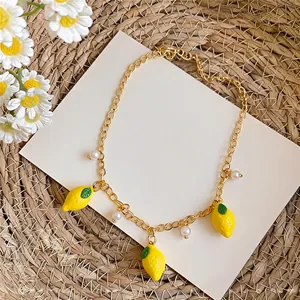 Close-up of a gold-colored necklace with lemon pendants and small white pearls