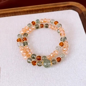 Vue détaillée de bracelets en perles empilés avec des pierres vertes et ambrées