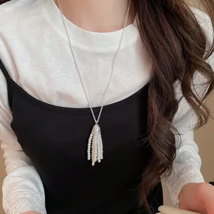 Detailansicht einer Vintage-Perlenkette mit Quasten über einem schwarz-weißen Outfit