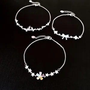 Detail of elegant silver bracelets featuring zircon butterfly, bow, and flower charms