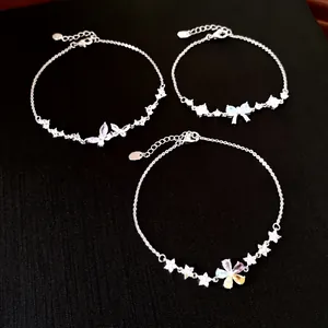 Macro view of three silver-tone bracelets featuring zircon butterfly, bow, and flower pendants.