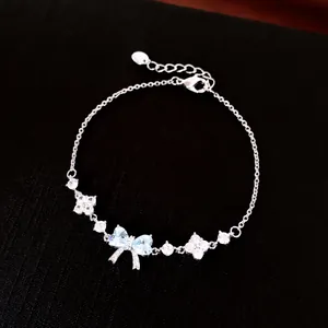 Close-up of silver-tone bracelet with light blue bow and flower zircon charms