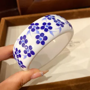 Detail view showing the elegant blue floral pattern on white resin bangle bracelet