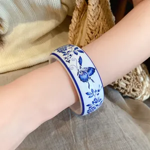 Elegant blue and white porcelain resin bangle with floral butterfly pattern on a wrist.
