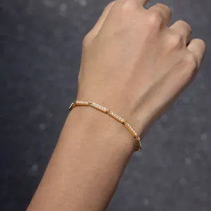 Vue détaillée d'un bracelet en acier inoxydable plaqué or 18 carats avec zircons au poignet.