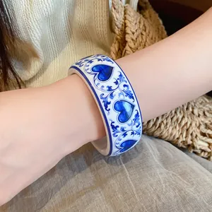 Detail shot of a resin bangle with blue and white porcelain heart patterns on an arm.