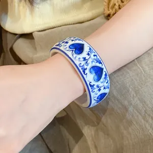 Close-up of a blue and white porcelain style resin bangle with heart and floral patterns