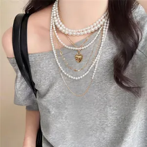 Elegante mehrlagige Perlenkette mit einem goldenen Herzanhänger am Hals des Models
