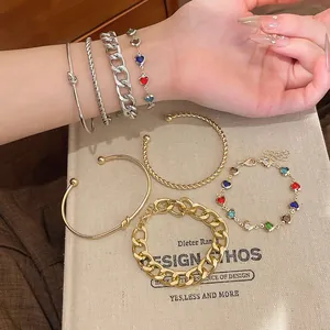 Detailaufnahme von Herz-Glasperlenarmband und goldenem gedrehtem Armreif-Schmuckset