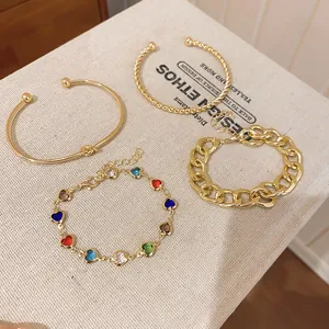 Nahaufnahme von vergoldetem Schmuckset mit Herzglasperlen und grober Kette.