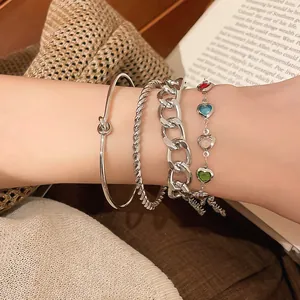 Nahaufnahme eines silberfarbenen Herz-Glasperlen-Armband-Sets und einer Armspange