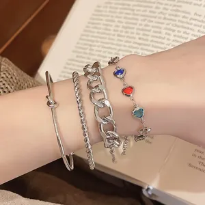 Detail eines silberfarbenen Armband-Sets mit bunten Herzanhängern am Handgelenk