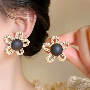 Gros plan de boucles d'oreilles fleurs vintage avec pétales tressés et centre brun.
