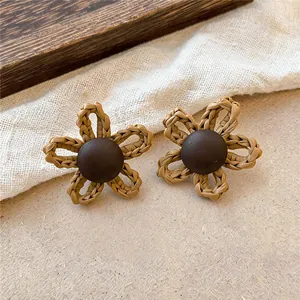 Gros plan sur des boucles d'oreilles vintage en raphia tressé avec centre en bois