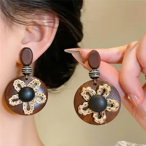 Gros plan de boucles d'oreilles rétro en bois avec pendentif fleur portées par un modèle