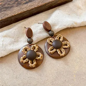 Gros plan sur les boucles d'oreilles vintage en bois et paille sur fond rustique