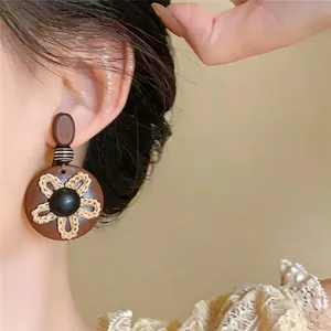 Gros plan d'une boucle d'oreille fleur vintage en bois marron portée par un mannequin