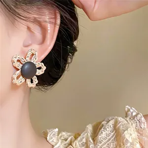 Détail en gros plan d'une boucle d'oreille fleur tissée rétro sur une oreille de mannequin.