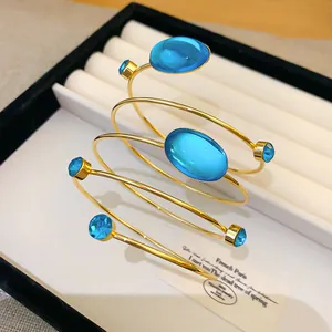 Gros plan sur un bracelet de bras bohème doré orné de cristaux bleus ovales