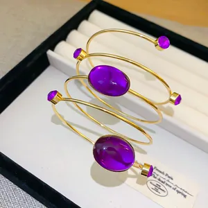 Gros plan d'un bracelet de bras rétro bohème en or avec gemmes ovales et cristaux violets