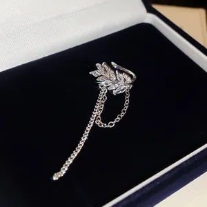 Detailaufnahme einer eleganten silbernen Ohrmanschette in Blattform mit funkelnden Kristallquasten