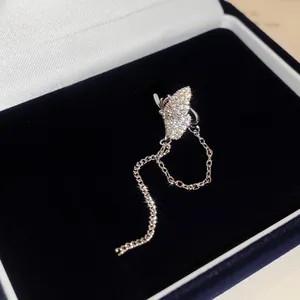 Detailansicht eines funkelnden Schmetterlings-Ohrklemms mit silbernen Ketten in Box