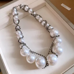 Elegante Perlenhalskette mit funkelnden Strasssteinen verziert in einer Schmuckschatulle.