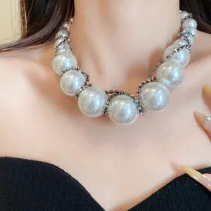Detailaufnahme einer Halskette mit großen weißen Perlen und Strass auf dem Modellhals