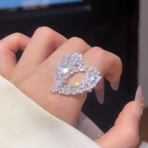 Close-up of a sparkling hollow heart-shaped ring with pavé zircons on a delicate hand