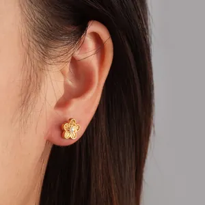 Nahaufnahme eines goldfarbenen Blumen-Ohrsteckers aus Edelstahl mit Zirkonia am Ohr