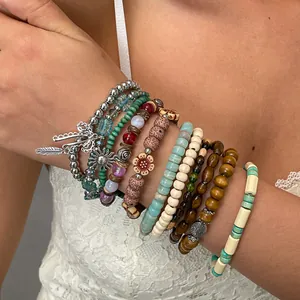 Close-up van een boheemse kralenarmbandset met bedeltjes van hout, hars en veren.