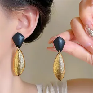 Detailansicht von Vintage-Ohrringen mit goldenen strukturierten Ovalen und schwarzen Spitzen