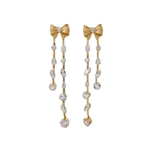 Elegante goldene Schleifenohrringe mit langen hängenden Zirkonia-Quasten auf Weiß