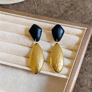 Nahaufnahme von geometrischen Vintage-Ohrsteckern mit strukturierter Gold- und Holzoptik
