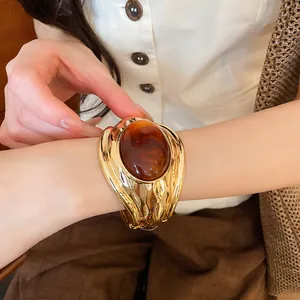 Nahaufnahme eines goldenen Armreifs mit großem bernsteinfarbenem Harzstein