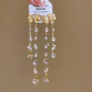Detailansicht eleganter goldener Schleifen-Quastenohrringe mit funkelnden Zirkonia