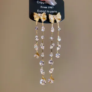 Detailansicht eleganter goldener Schleifenohrringe mit funkelnden Zirkonia-Kristallen.