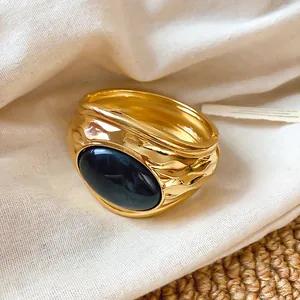 Detail eines goldenen Armreifs mit Falten-Optik und großem ovalen blauen Harzstein