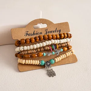 Detail van 6-delige etnische armbandset met houten kralen en zilveren veren hangers.