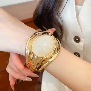 Nahaufnahme eines goldenen Armreifs mit einer großen weißen ovalen Harzeinlage