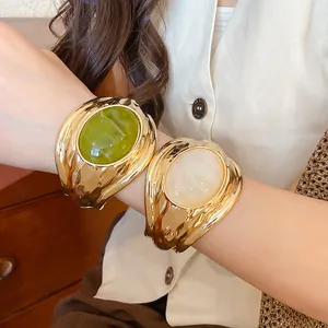 Detailansicht der goldfarbenen Manschettenarmbänder mit grünem und weißem Harzstein