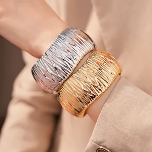 Massive gold- und silberfarbene Armreifen mit ausgeprägter Faltenstruktur für moderne Mode-Looks