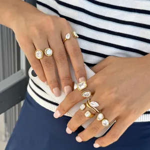 Detailed close-up of various 18k gold plated stainless steel zircon rings on model's hands.
