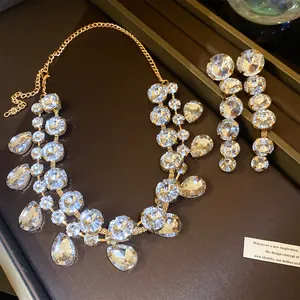 Makrodetail eines Goldschmucksets mit funkelnden Tropfen- und runden Strasssteinen.